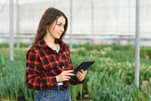 Beautiful young smiling girl, worker with flowers in greenhouse. Concept work in the greenhouse, flowers. photo