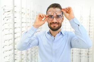 Glasses Shop. Man Trying On Eyeglasses In Optics Store photo