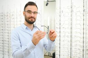 Man choosing glasses in eyewear store photo