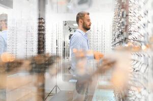 Man choosing glasses in eyewear store photo