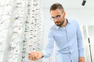 Man choosing glasses in eyewear store photo