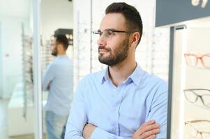 Glasses Shop. Man Trying On Eyeglasses In Optics Store photo