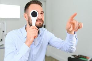 prueba de vista. hombre es comprobación su visión adentro en el clínica foto