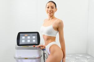 Happy young woman after laser hair removal. A woman near a laser depilation machine photo