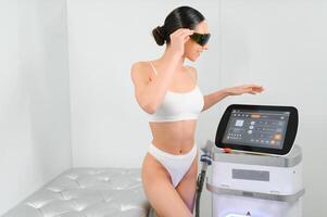 Happy young woman after laser hair removal. A woman near a laser depilation machine photo