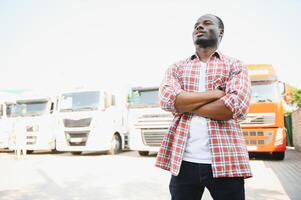 negro hombre camión conductor cerca su camión estacionado en un estacionamiento lote a un camión detener. foto