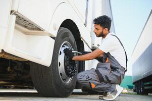 Indian Mechanic unscrews wheel truck pneumatic wrench photo