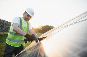 Side view of male worker installing solar modules and support structures of photovoltaic solar array. photo