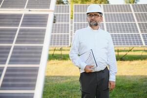 Solar power plant. Man standing near solar panels. Renewable energy photo