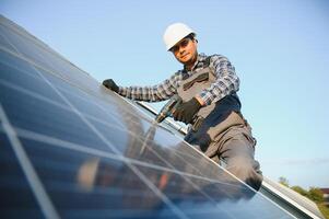 un indio trabajador en uniforme y con herramientas trabajos en un solar panel granja foto