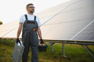 Portrait of senior worker in uniform standing near solar panels photo