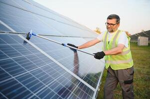 Worker cleaning solar panels after installation outdoors. photo