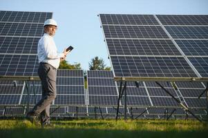 Solar power plant. Man standing near solar panels. Renewable energy photo