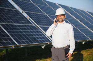 Solar power plant. Man standing near solar panels. Renewable energy photo