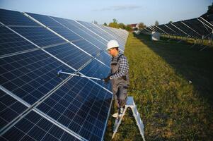 Indian handyman cleaning solar panels form dust and dirt photo