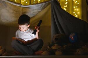 the child is reading a book with a flashlight photo