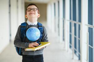 colegial con bolsa para la escuela y libros en el escuela. educación concepto. espalda a escuela. colegial yendo a clase. elegante chico con mochila. chico Listo a estudiar. foto