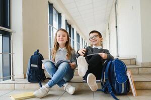 Portrait of smiling school kids in school corridor with books photo