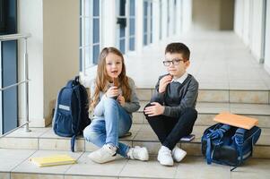 Group of classmates having lunch during break with focus on smiling girl with apple. photo