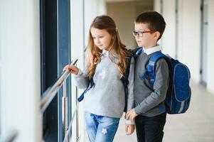 Portrait of smiling school kids in school corridor with books photo