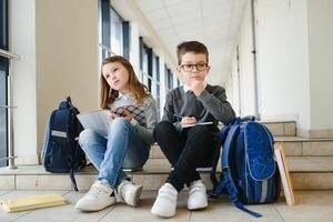 Portrait of smiling school kids in school corridor with books photo