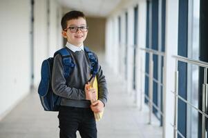 Happy cute clever boy in glasses with school bag and book in his hand. First time to school. Back to school. photo