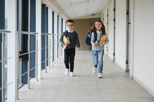 Portrait of smiling school kids in school corridor with books photo