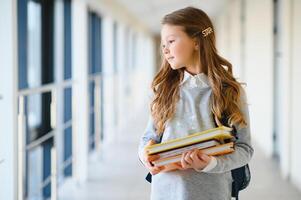 Portrait of a beautiful girl with books at school. Learning concept. photo