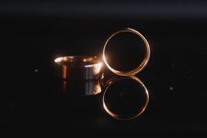 Elegant wedding rings for the bride and groom on a black background with highlights, macro, selective focus. photo