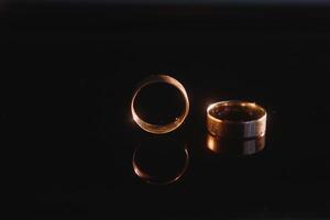 Elegant wedding rings for the bride and groom on a black background with highlights, macro, selective focus. photo