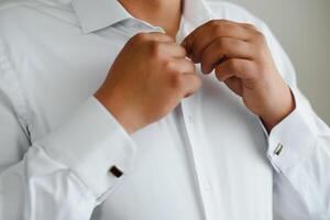 A man fastens buttons on his shirt photo