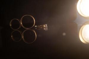 Elegant wedding rings for the bride and groom on a black background with highlights, macro, selective focus. photo