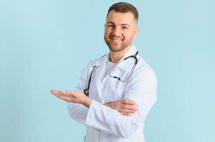 Horizontal banner of smiling young male doctor showing and presenting something with hand, isolated on blue background with copy space on the left side. photo