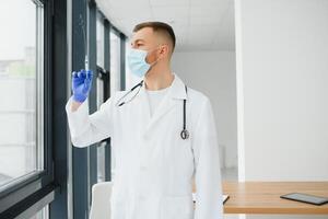 Doctor in PPE holding a vial or bottle vaccine against coronavirus Covid 19 new Omicron variant or strain in his hand, close up. Concept of vaccination, trial and treatment due to SARS-CoV-2 pandemic. photo