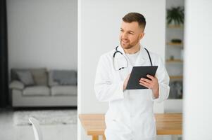 Young male cancer specialist in labcoat using digital tablet at clinic photo