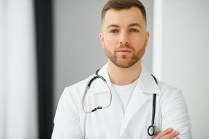 Portrait of smiling doctor looking at camera with arms crossed in medical office. photo