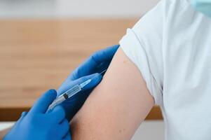 Doctor making a vaccination in the shoulder of patient Disabled person, Flu Vaccination Injection on Arm, coronavirus, covid-19 vaccine disease preparing for human clinical trials vaccination shot. photo