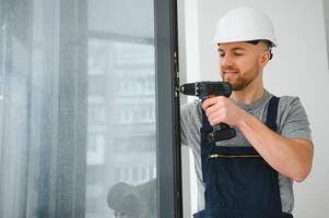 handsome young man installing bay window in new house construction site photo