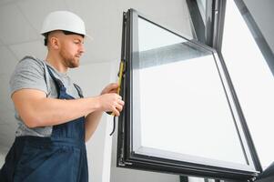 Construction worker repairing plastic window with screwdriver indoors, space for text. Banner design photo