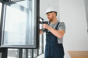 Construction worker repairing plastic window with screwdriver indoors, space for text. Banner design photo