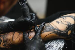 tattooist with his machine tattooing on the arm with the design drawn, concept of art and design photo