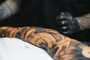 tatuador con su máquina tatuajes en el brazo con el diseño dibujado, concepto de Arte y diseño foto