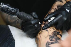 tattooist with his machine tattooing on the arm with the design drawn, concept of art and design photo