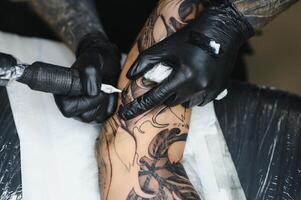 tattooist with his machine tattooing on the arm with the design drawn, concept of art and design photo