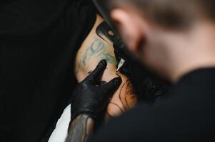 tattooist with his machine tattooing on the arm with the design drawn, concept of art and design photo