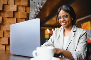 suerte día. emocional negro mujer mirando a computadora portátil, apretando puños y gritando, trabajando a cafetería, Copiar espacio foto