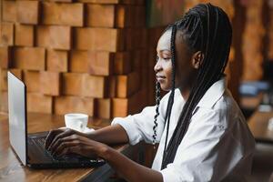 suerte día. emocional negro mujer mirando a computadora portátil, apretando puños y gritando, trabajando a cafetería, Copiar espacio foto
