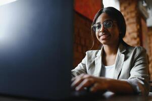 Focused young african american businesswoman or student looking at laptop, serious black woman working or studying with computer doing research or preparing for exam online photo