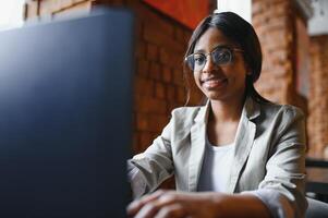 Happy african american woman worker using laptop work study at computer in loft office or cafe, smiling mixed race female student freelancer using pc app dating communicating online watching webinar photo