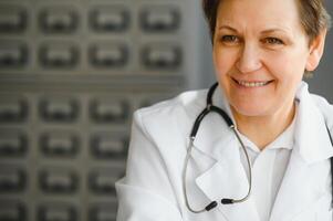 retrato de maduro hembra médico en blanco Saco a lugar de trabajo foto